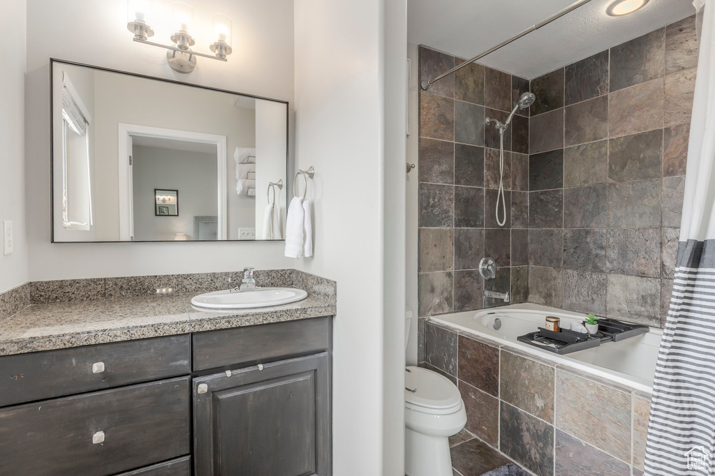 Bathroom featuring tiled shower / bath combo, vanity, and toilet