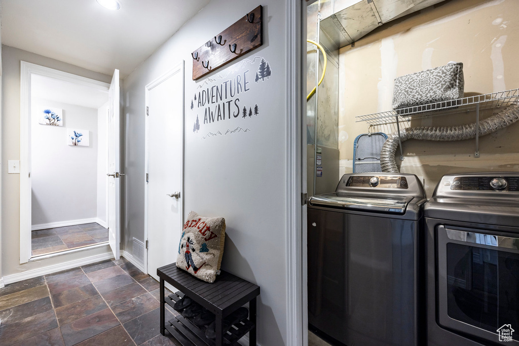 Laundry room featuring separate washer and dryer, stone tile floors, and baseboards