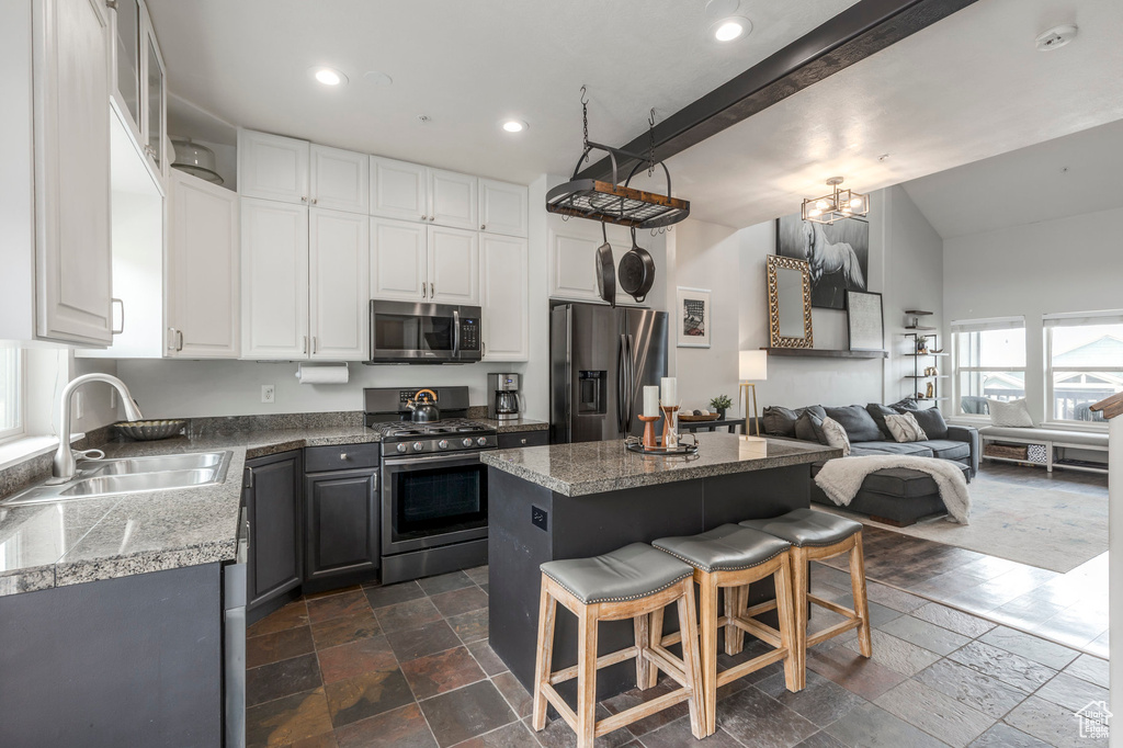 Kitchen with stainless steel appliances, a sink, stone tile floors, a kitchen island, and tile countertops