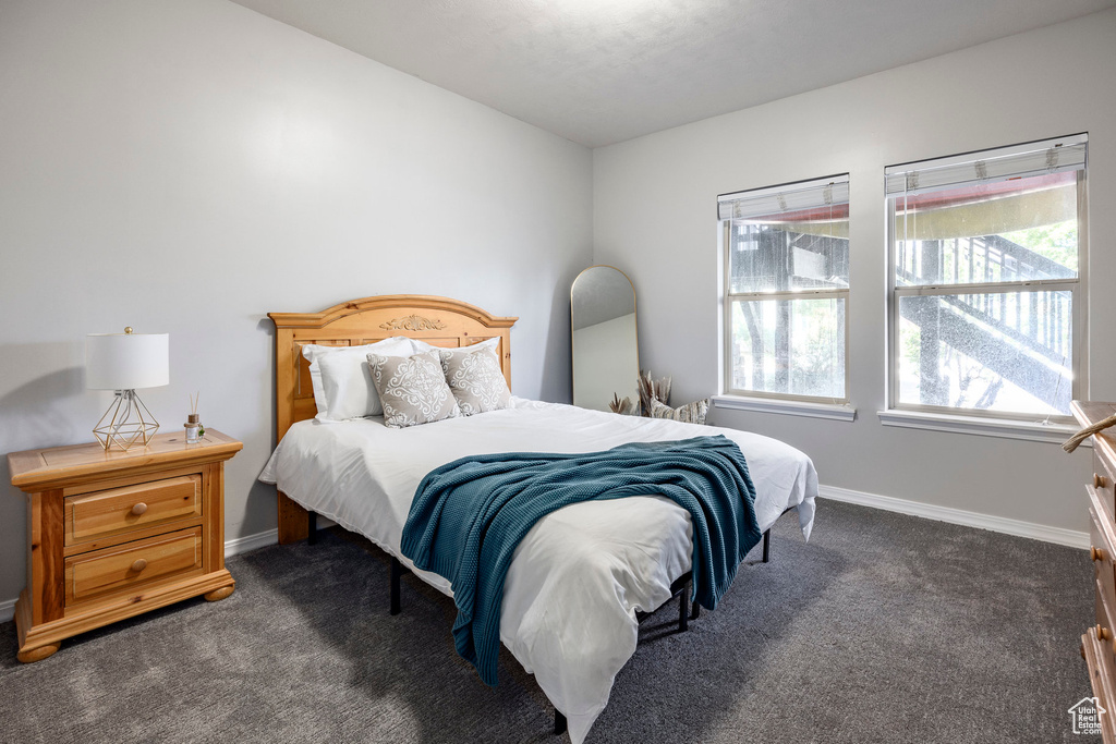 Bedroom with dark carpet and baseboards
