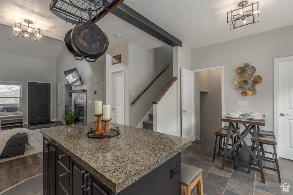 Kitchen with open floor plan, a center island, dark stone countertops, dark cabinetry, and lofted ceiling