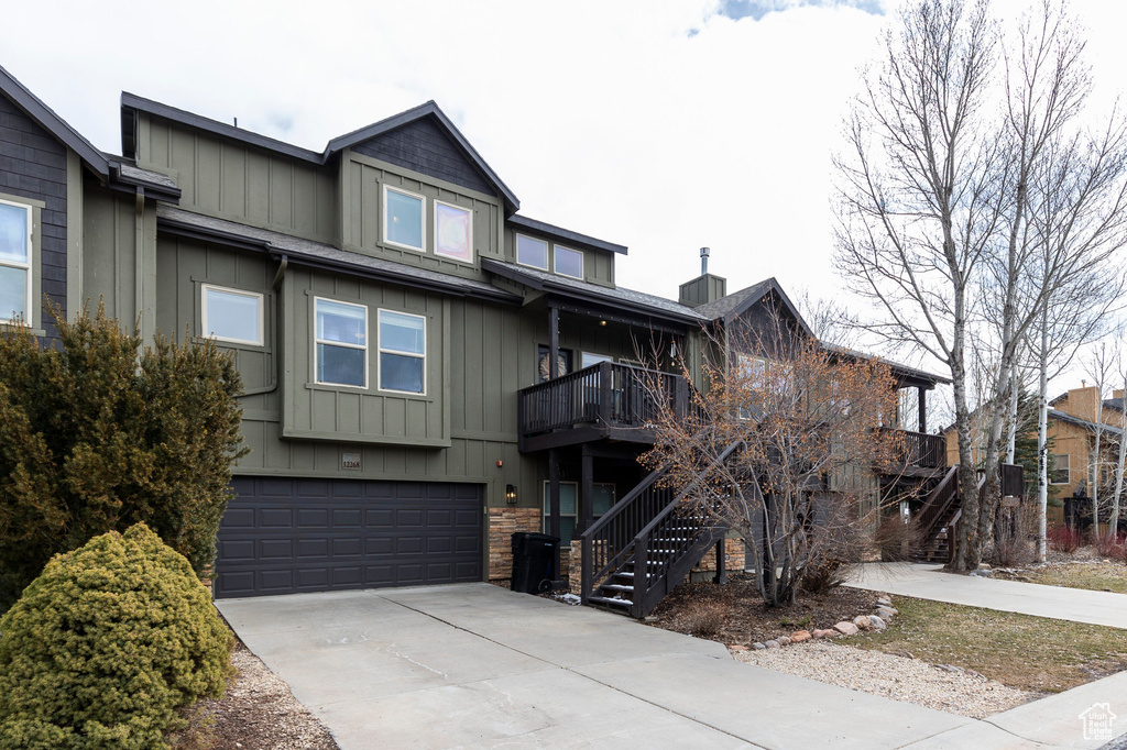 Multi unit property with board and batten siding, a garage, driveway, and stairway