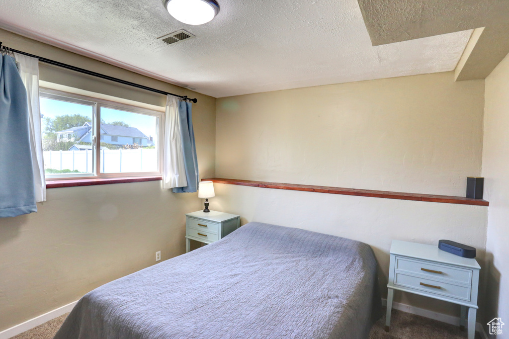 Carpeted bedroom with a textured ceiling, baseboards, and visible vents