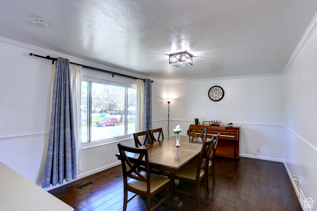Dining space with hardwood / wood-style floors, visible vents, and ornamental molding
