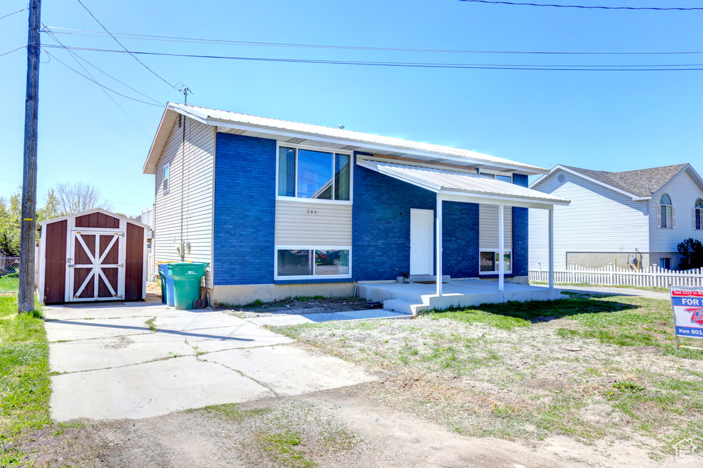 View of front of home with a storage shed, fence, an outbuilding, a porch, and metal roof