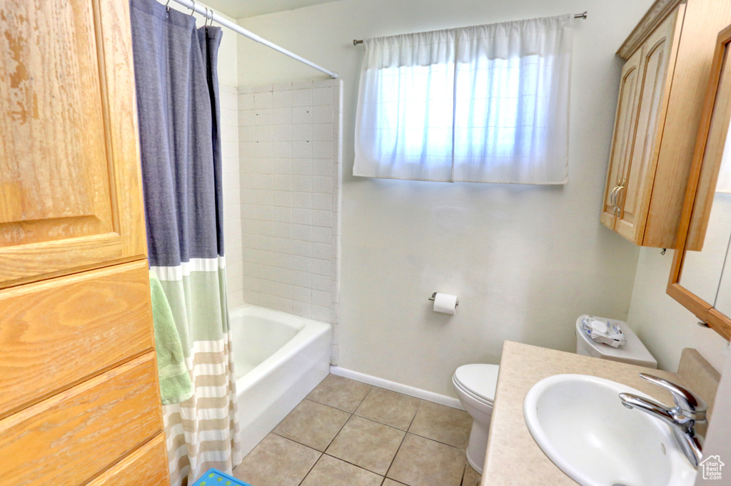 Full bathroom with tile patterned floors, toilet, baseboards, shower / tub combo with curtain, and vanity