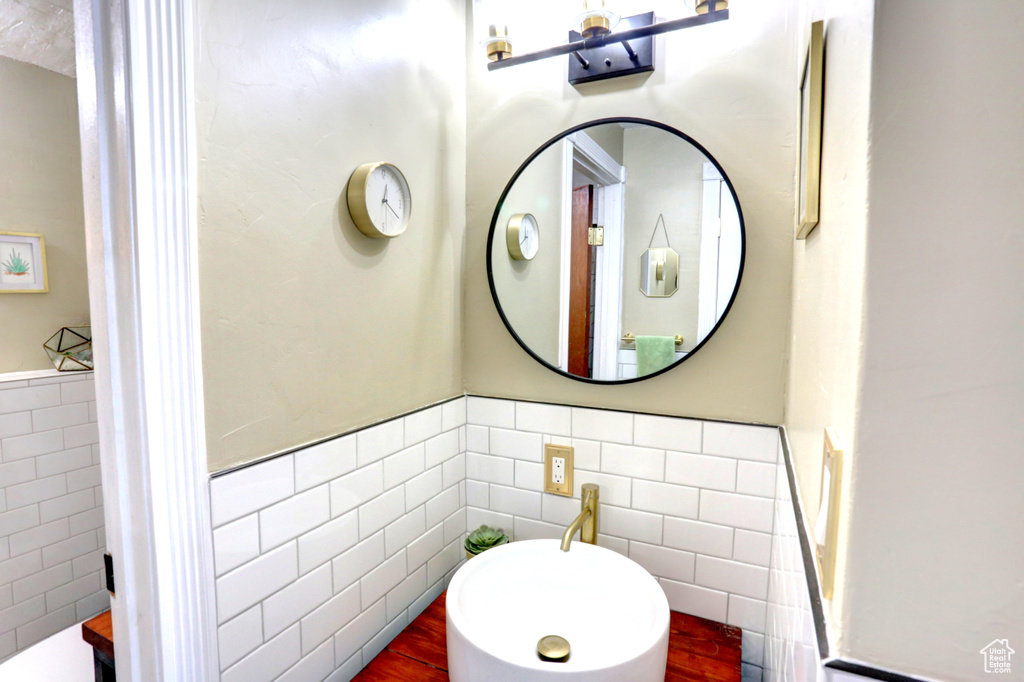 Half bathroom with wainscoting and tile walls