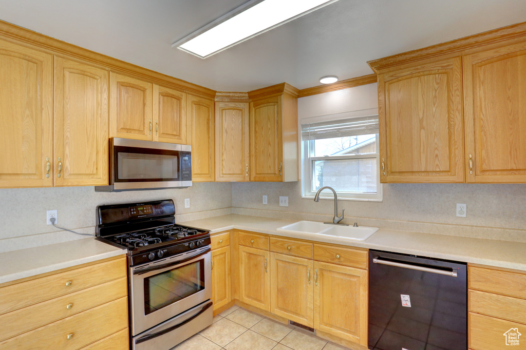 Kitchen featuring light brown cabinetry, stainless steel appliances, light countertops, and a sink