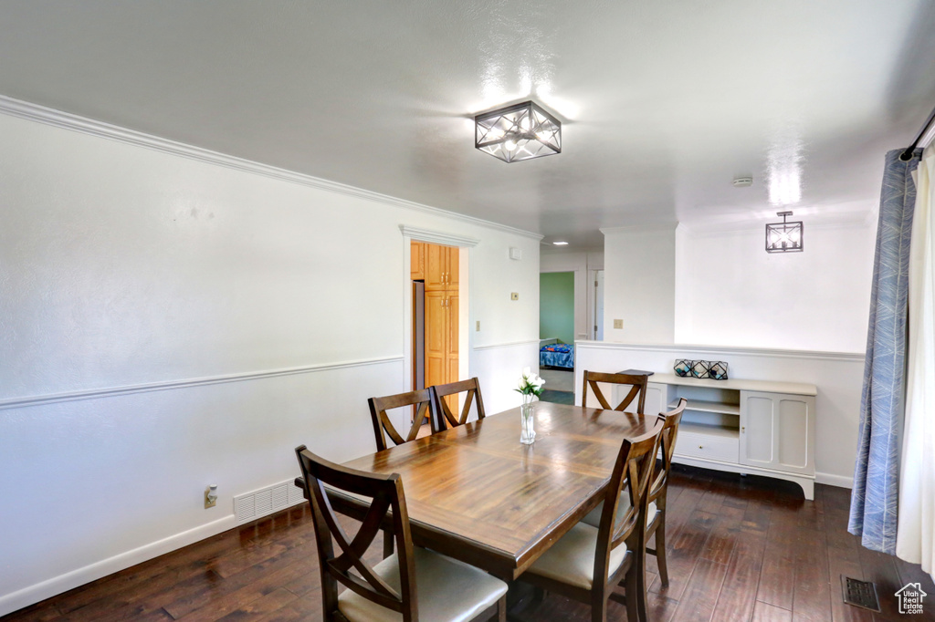 Dining room with hardwood / wood-style flooring, baseboards, ornamental molding, and visible vents