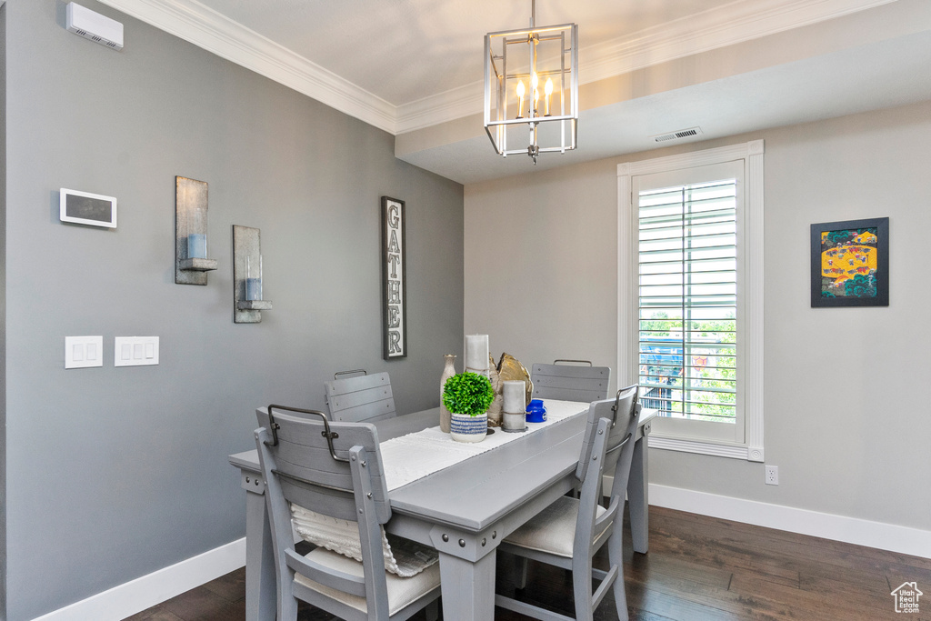 Dining area featuring visible vents, baseboards, ornamental molding, a chandelier, and dark wood-type flooring