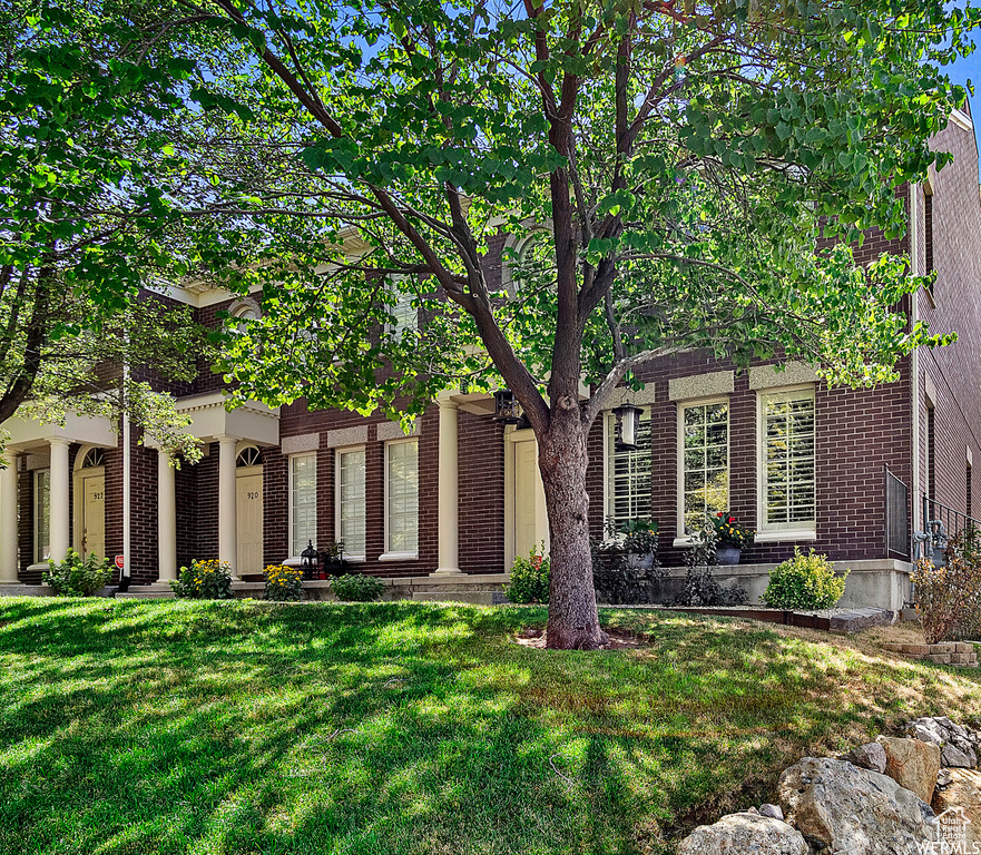 View of front facade featuring a front yard and brick siding