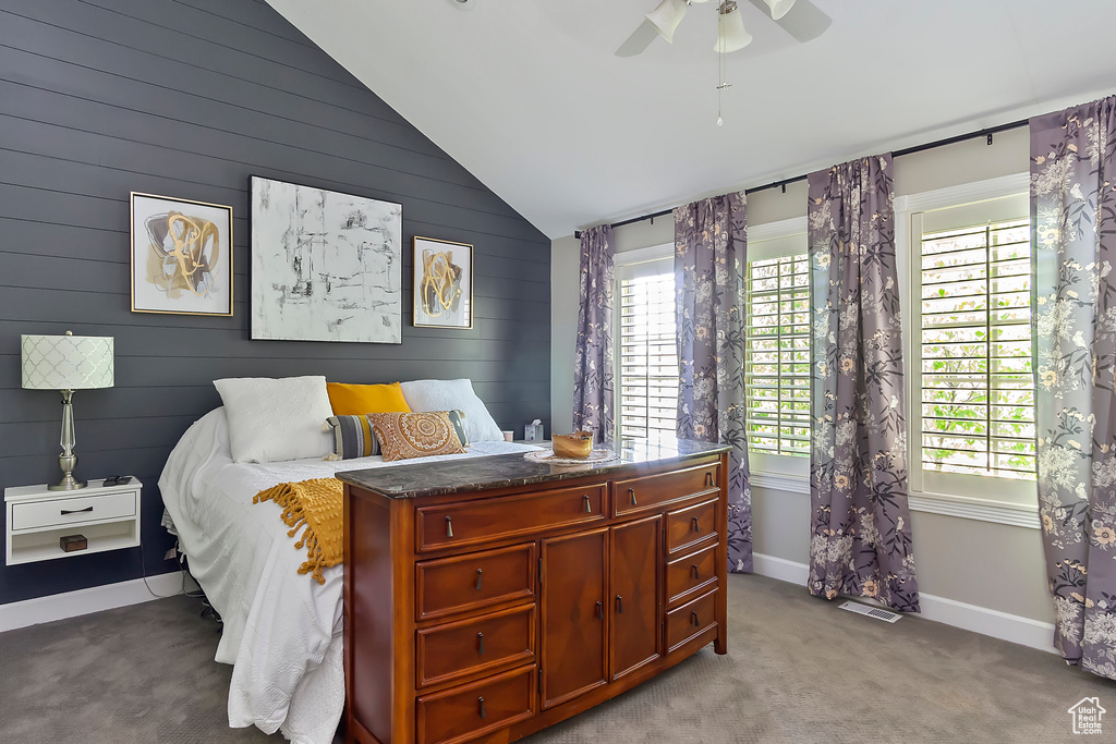 Bedroom featuring light carpet, baseboards, multiple windows, and lofted ceiling