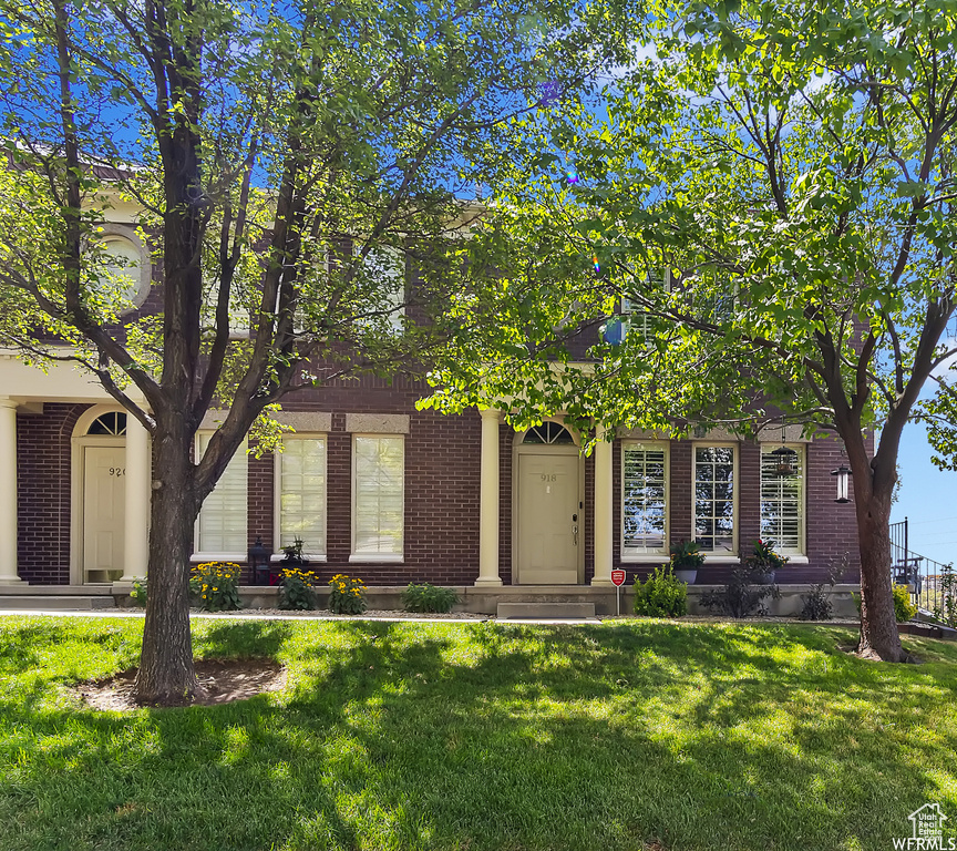 Obstructed view of property featuring a front yard and brick siding