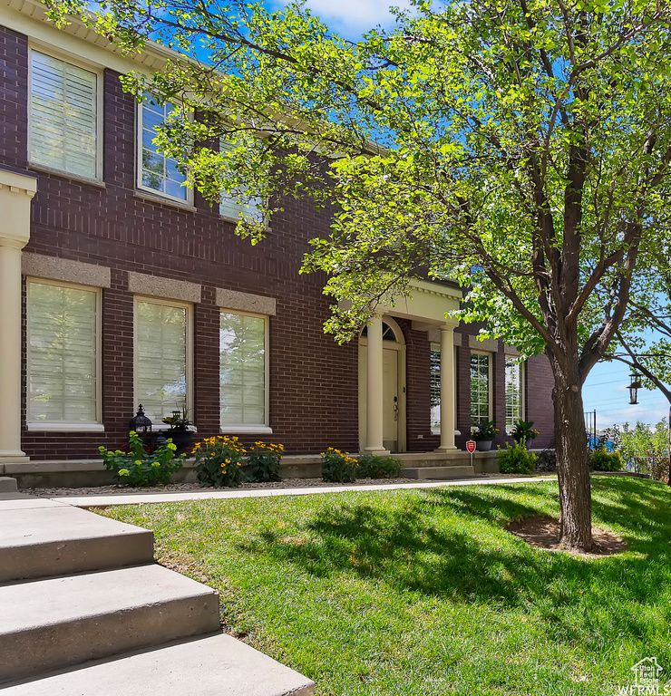 View of front facade featuring a front yard and brick siding