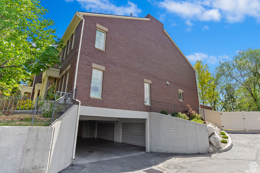 View of side of home featuring a garage, fence, and a gate