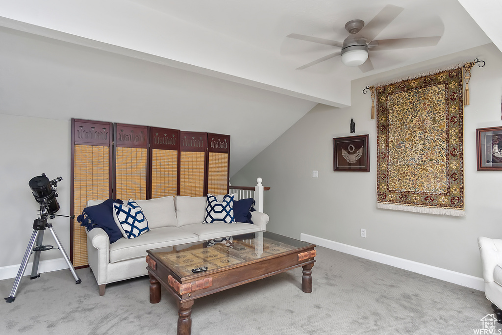 Living area with vaulted ceiling with beams, ceiling fan, baseboards, and carpet flooring
