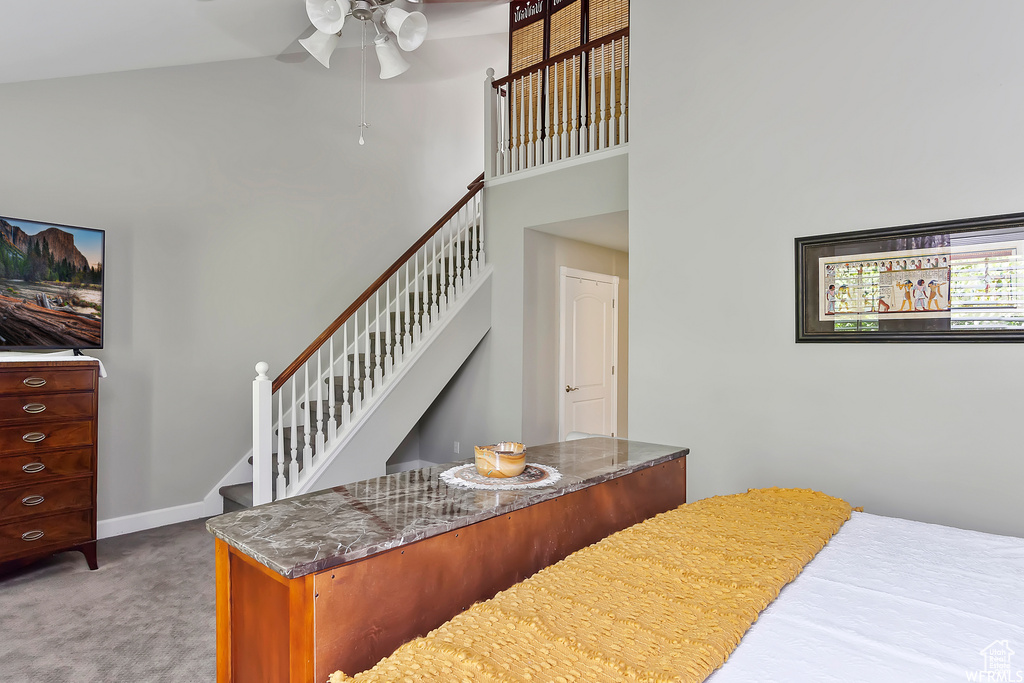 Bedroom with carpet floors, baseboards, ceiling fan, and a towering ceiling