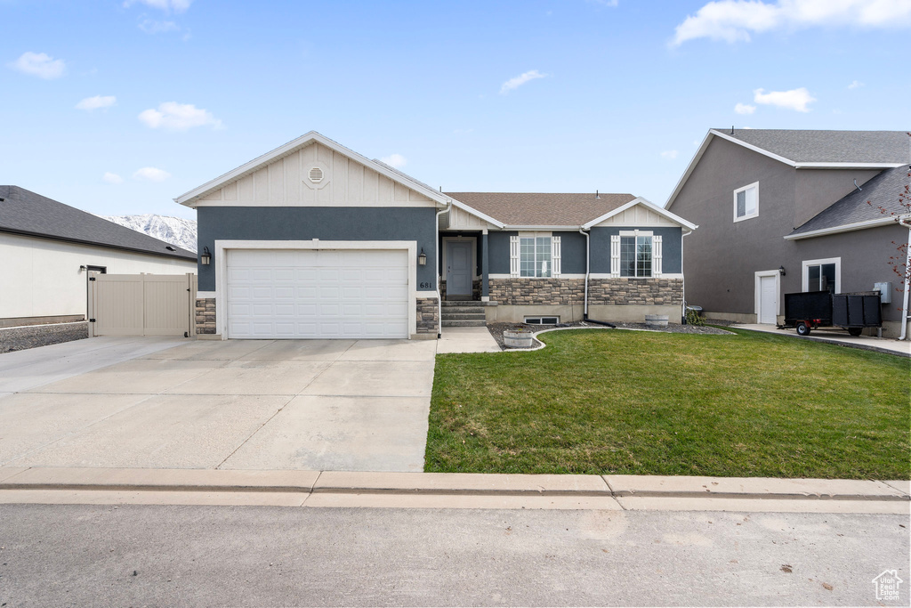 Ranch-style home featuring driveway, stone siding, an attached garage, a front yard, and fence