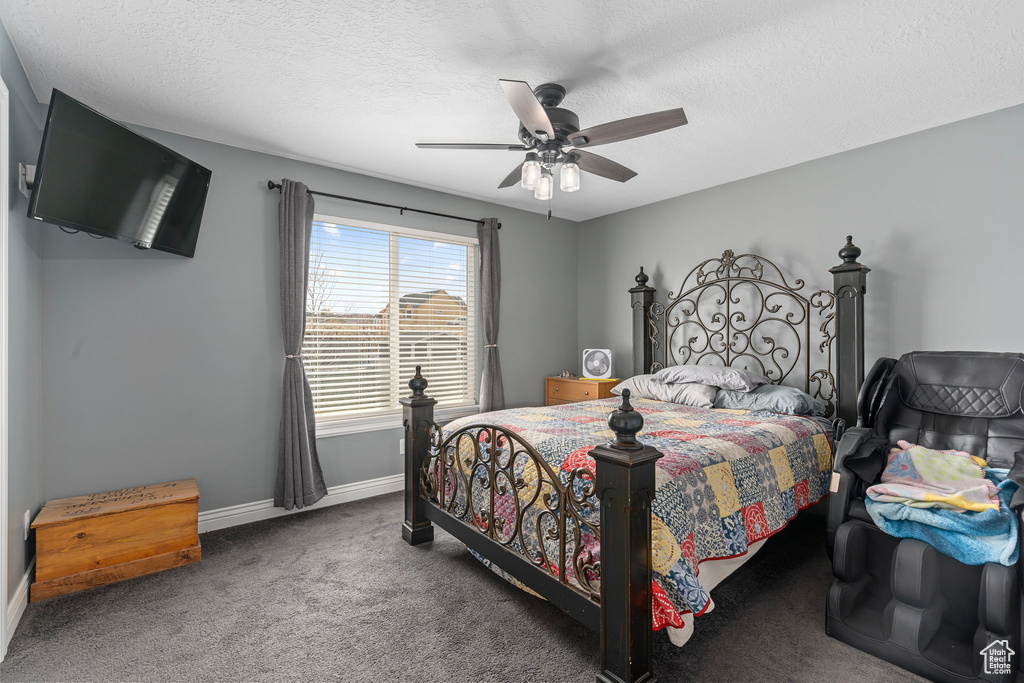 Carpeted bedroom featuring a textured ceiling, ceiling fan, and baseboards