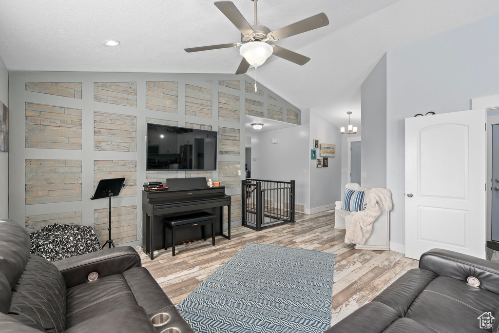 Living room with baseboards, vaulted ceiling, a ceiling fan, and wood finished floors