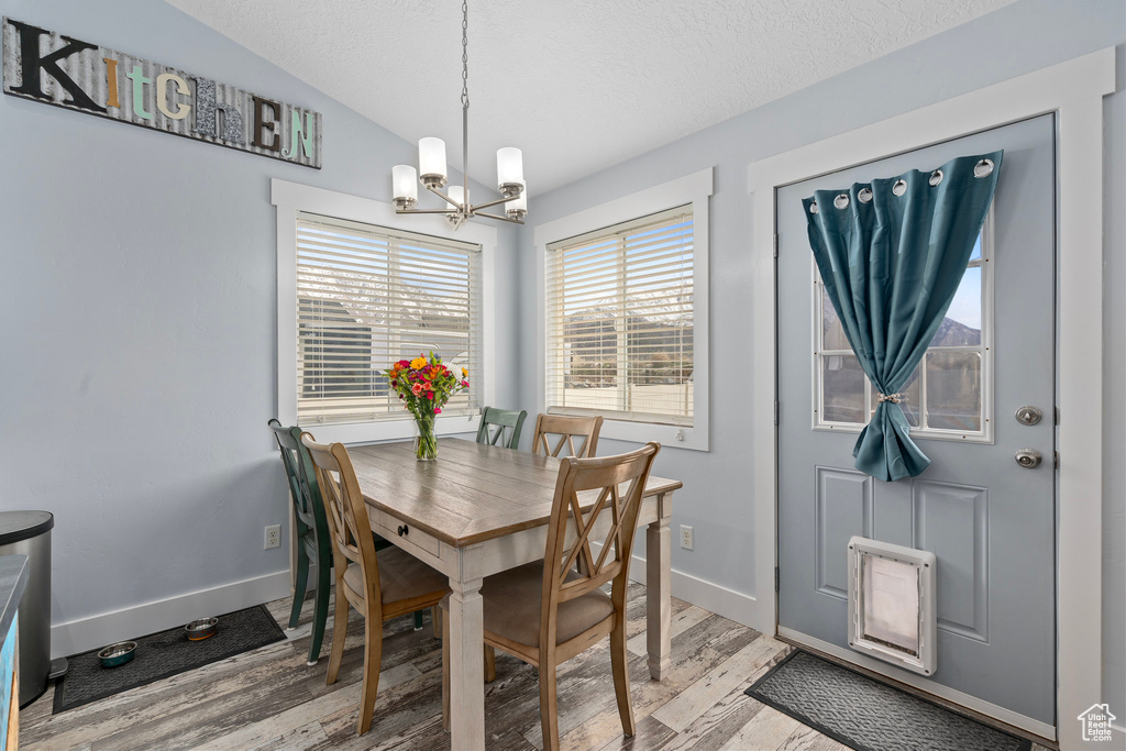 Dining space with a chandelier, lofted ceiling, baseboards, and wood finished floors