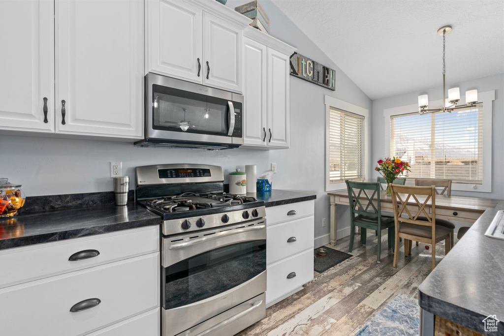 Kitchen with dark countertops, vaulted ceiling, and stainless steel appliances