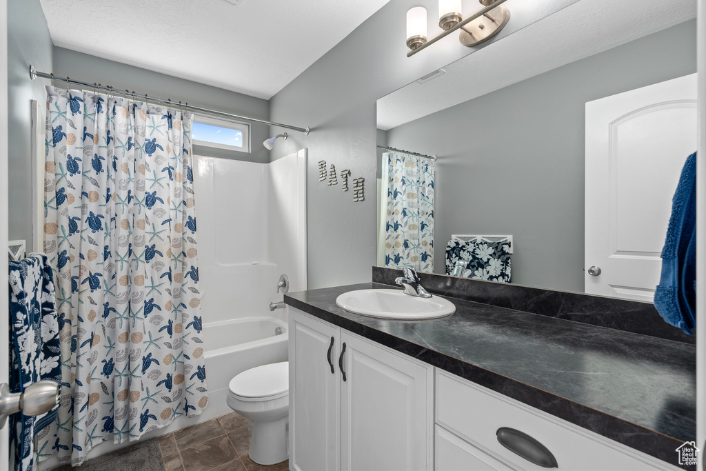 Bathroom with toilet, shower / bath combo with shower curtain, and vanity