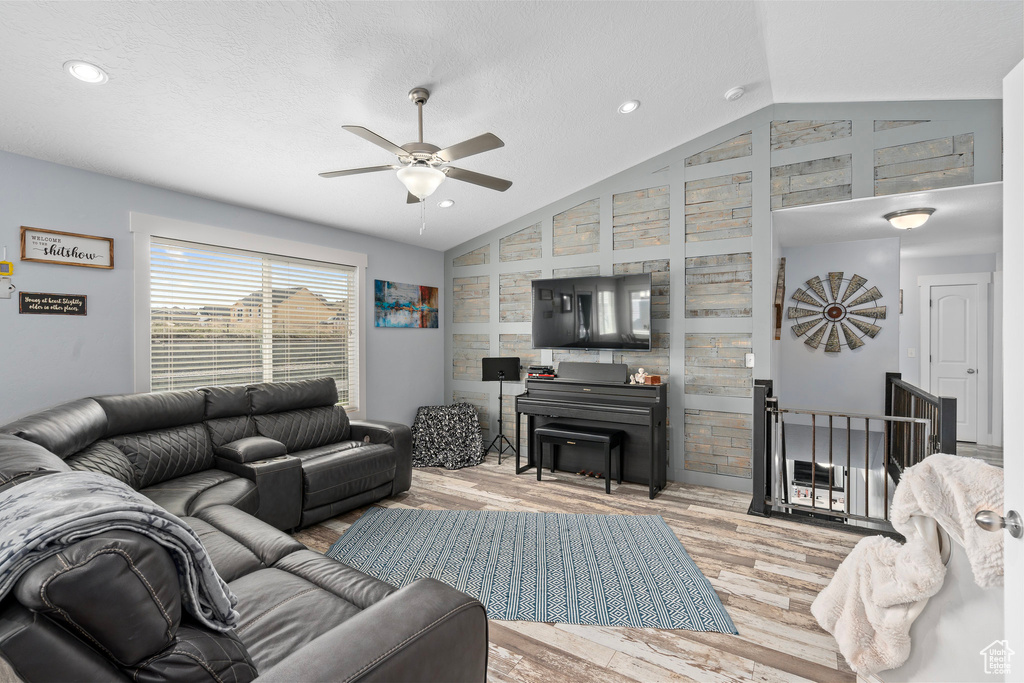 Living room with a textured ceiling, a ceiling fan, vaulted ceiling, recessed lighting, and wood finished floors