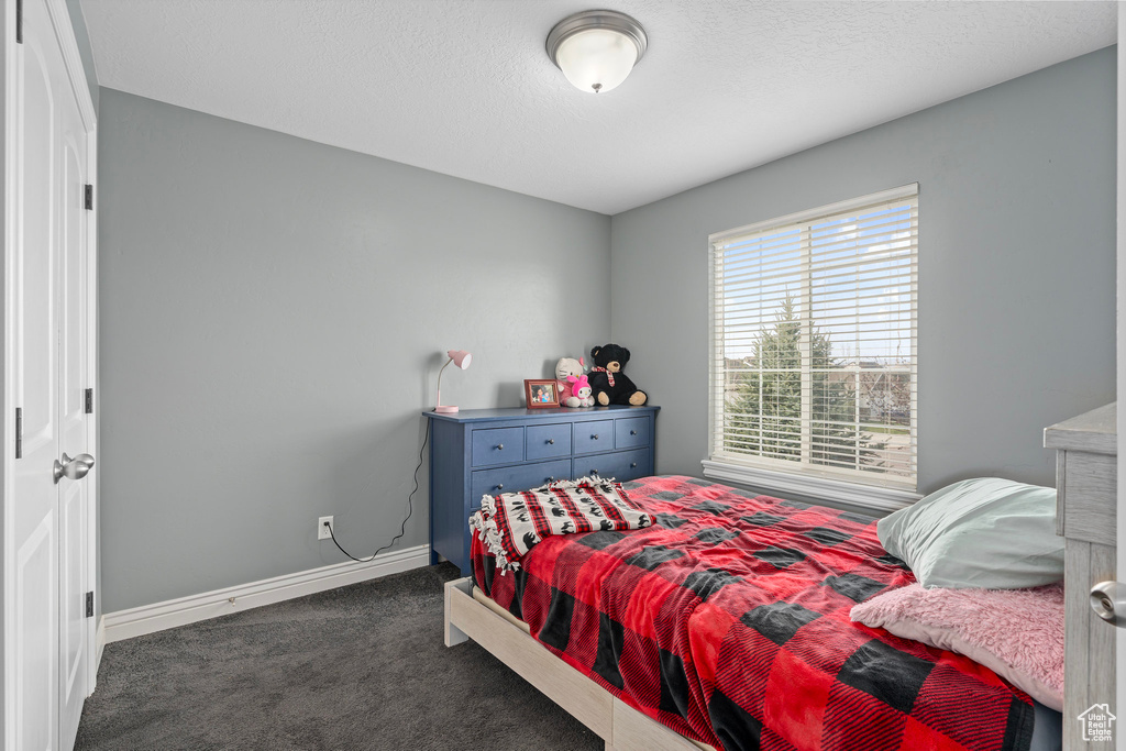 Carpeted bedroom with baseboards and a textured ceiling