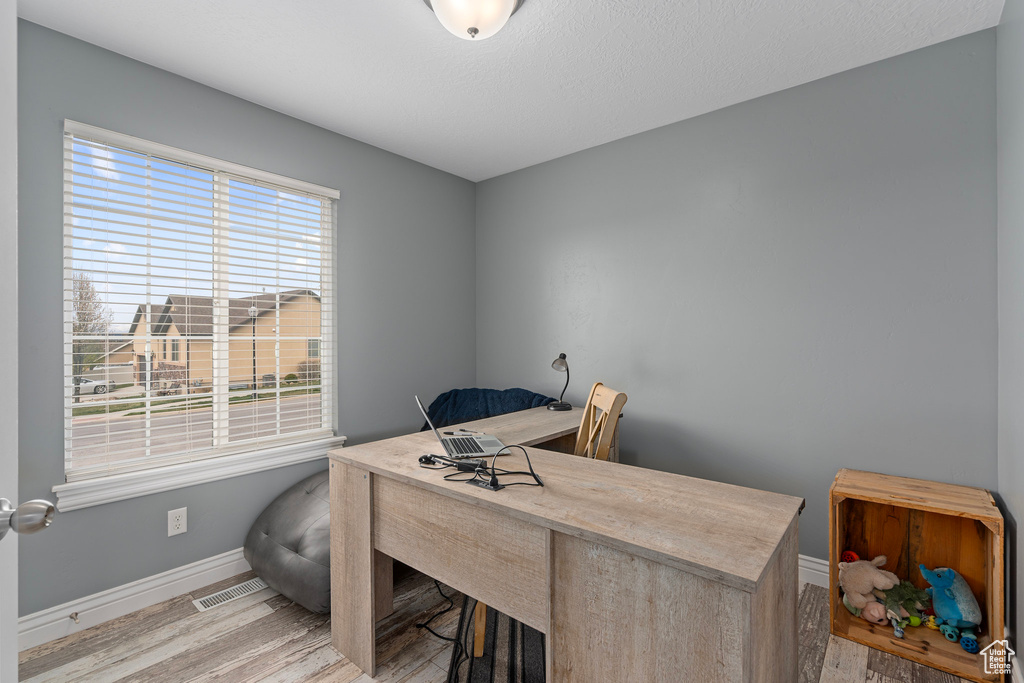 Office space featuring light wood-style floors, visible vents, and baseboards