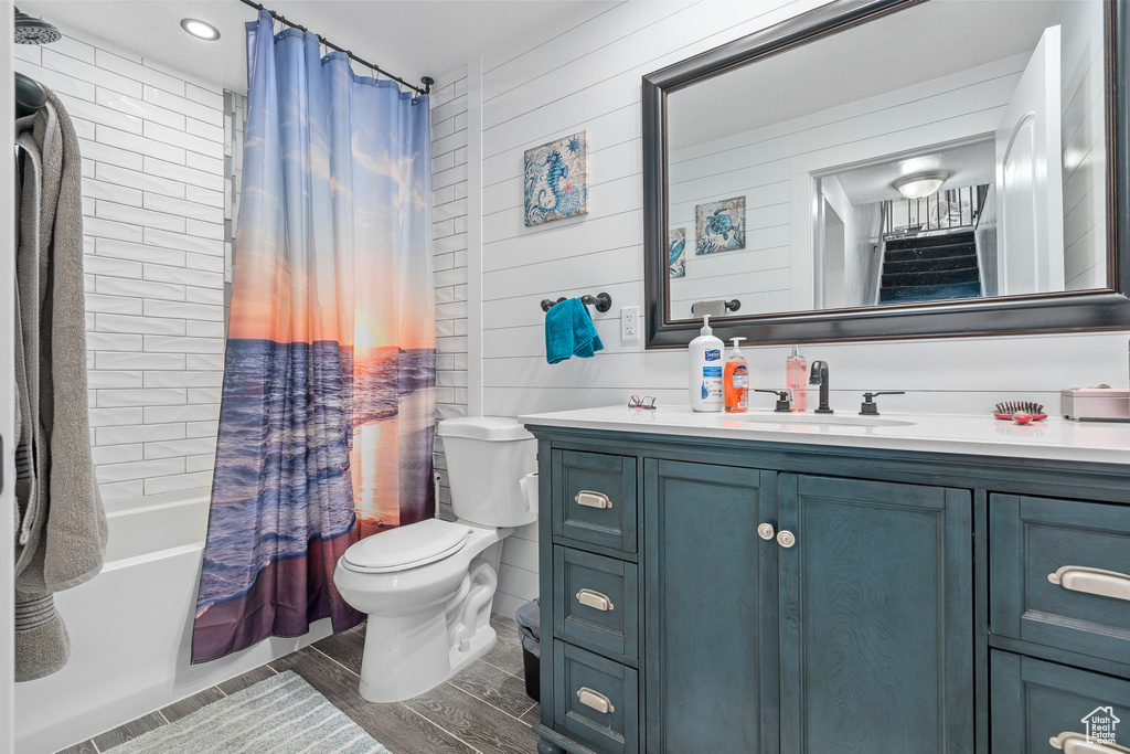 Full bathroom featuring toilet, shower / bath combo with shower curtain, vanity, and wood finish floors