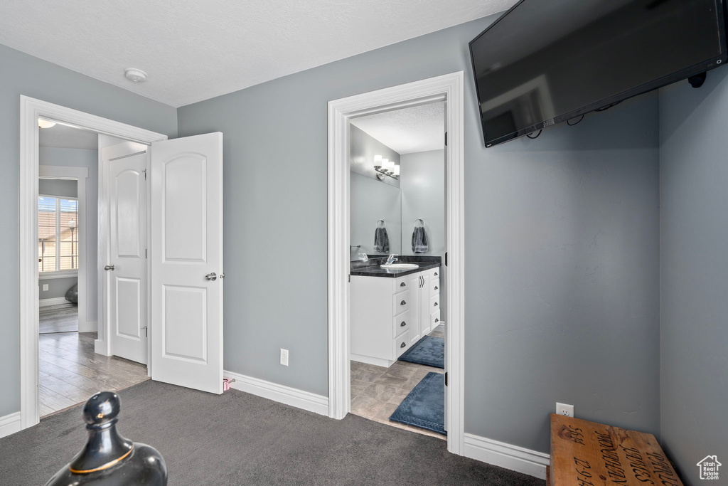 Bedroom with baseboards, a sink, carpet, and ensuite bath
