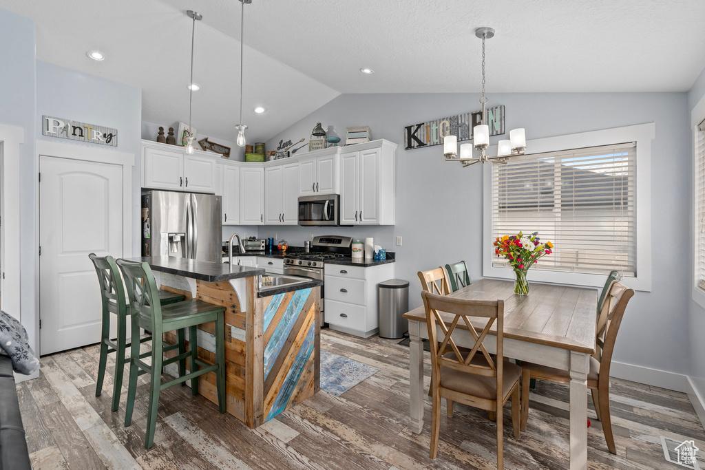 Kitchen featuring visible vents, appliances with stainless steel finishes, dark countertops, lofted ceiling, and a notable chandelier