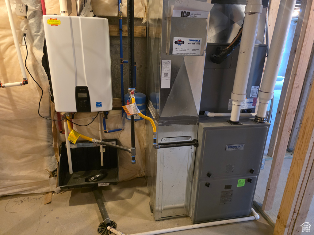 Utility room featuring tankless water heater and heating unit