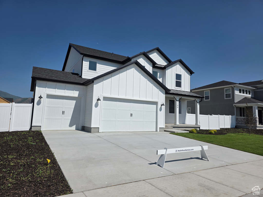 Modern farmhouse with an attached garage, board and batten siding, driveway, a standing seam roof, and metal roof