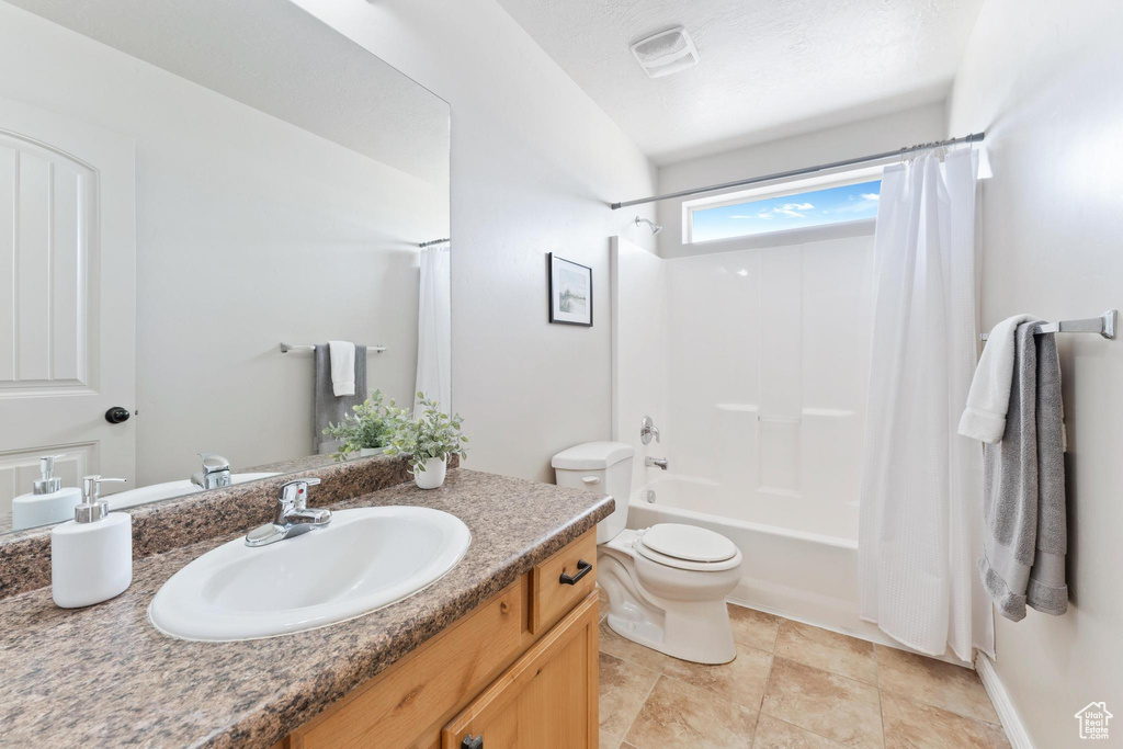Full bathroom with toilet, vanity, shower / bath combo with shower curtain, and visible vents
