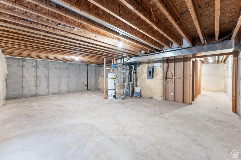Unfinished below grade area featuring secured water heater and electric panel