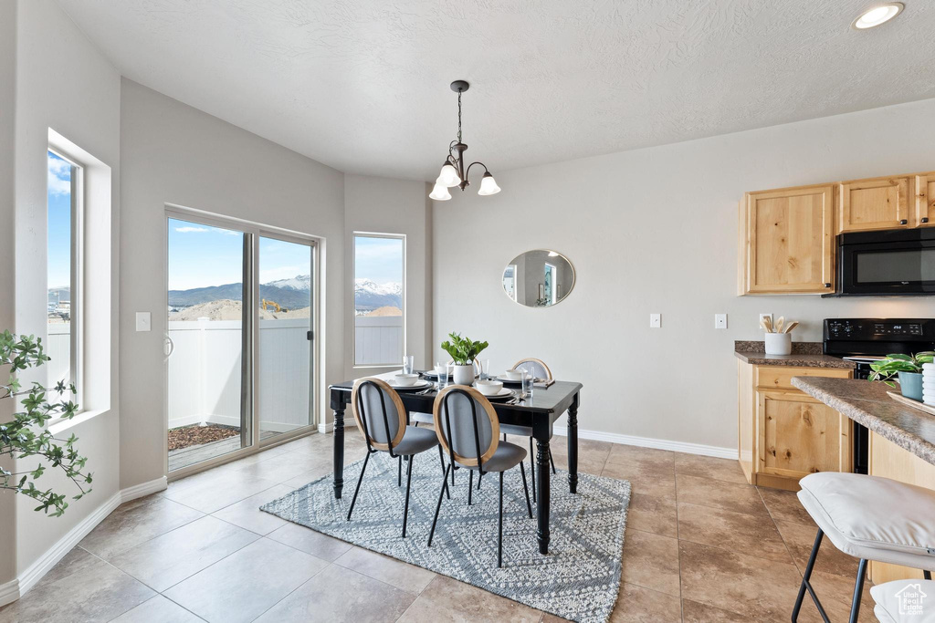 Dining room with a textured ceiling, a mountain view, baseboards, and an inviting chandelier