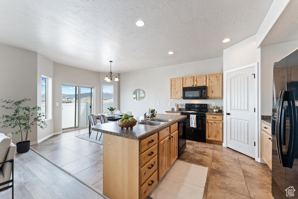 Kitchen featuring a notable chandelier, a sink, dark countertops, light brown cabinetry, and black appliances