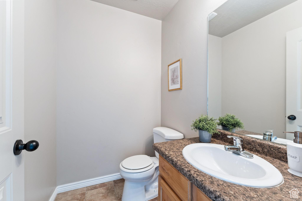 Half bathroom with toilet, vanity, and baseboards