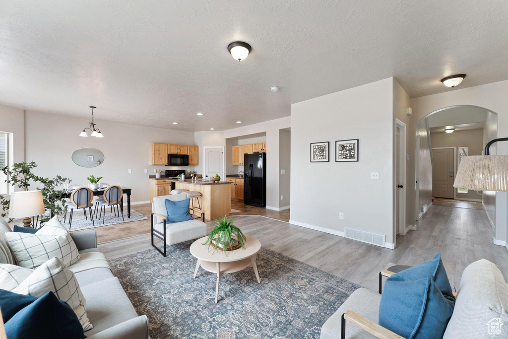 Living area with visible vents, baseboards, arched walkways, light wood finished floors, and recessed lighting