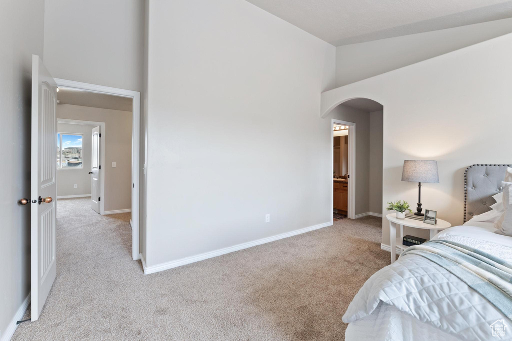 Bedroom featuring arched walkways, high vaulted ceiling, baseboards, and carpet floors