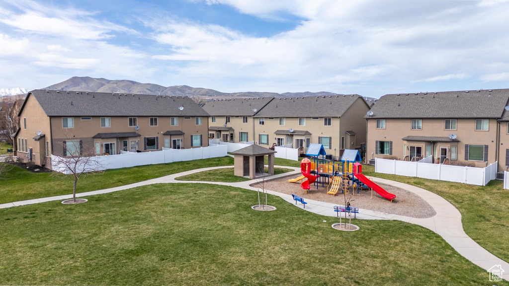 View of play area featuring a mountain view, fence, a residential view, and a lawn