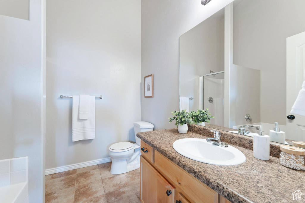 Full bathroom with baseboards, toilet, vanity, tile patterned floors, and a stall shower