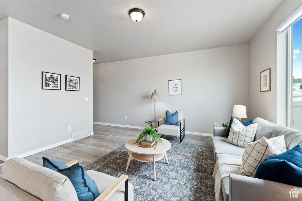 Living room with wood finished floors, baseboards, and visible vents