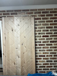 Bathroom with ornamental molding and brick wall