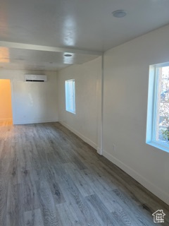 Spare room featuring baseboards, a wall unit AC, and wood finished floors