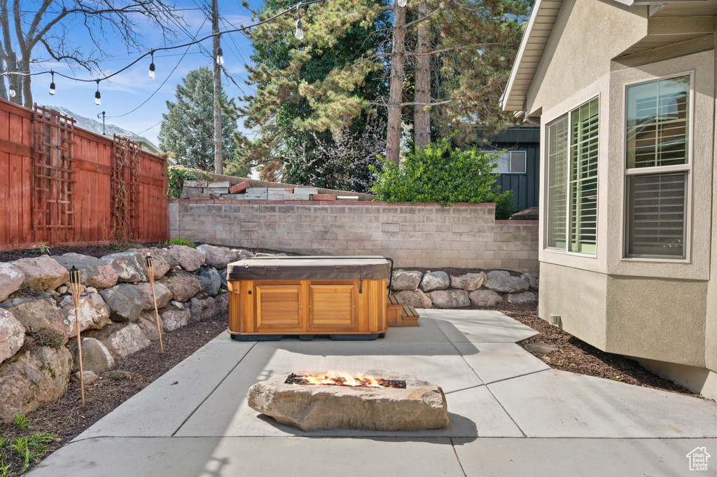 View of patio with a fire pit, fence private yard, and a hot tub
