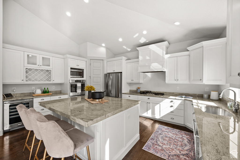 Kitchen with a center island, white cabinetry, appliances with stainless steel finishes, beverage cooler, and a sink