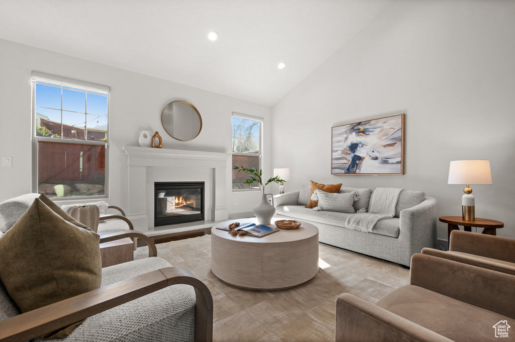 Living area featuring a glass covered fireplace, recessed lighting, high vaulted ceiling, and a healthy amount of sunlight